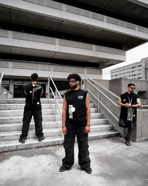 Three individuals in black outfits standing on concrete steps with a modern building in the background.